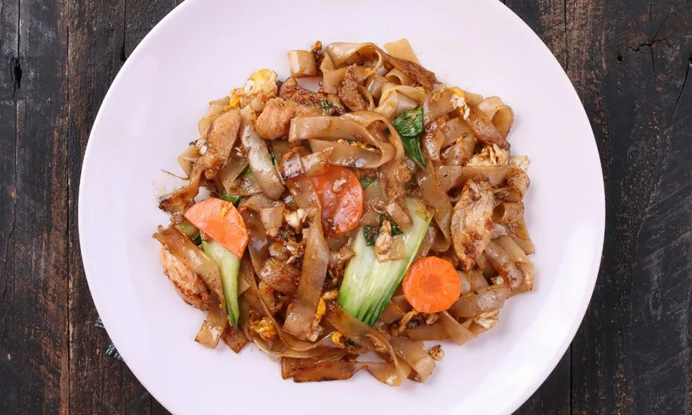 Wide rice noodles stir-fried with chicken, egg, and vibrant vegetables at Golden Dragon Express, a Chinese Restaurant in San Antonio